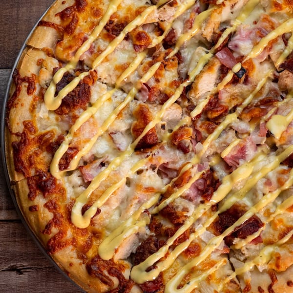Close-up of a This Guy's Pizza chicken and bacon pizza with a mustard drizzle.