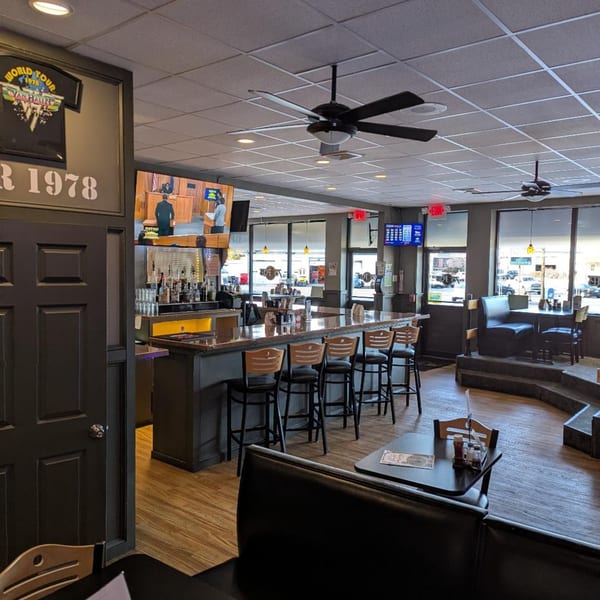 The 78 Pub's interior, featuring a long bar with stools, booths, and a large TV.