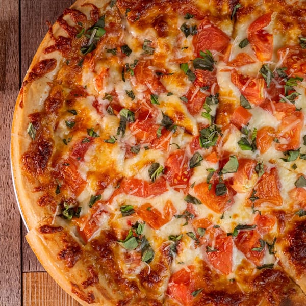 Close-up of a freshly baked pizza from The 78 Pub, topped with melted cheese, diced tomatoes, and basil.