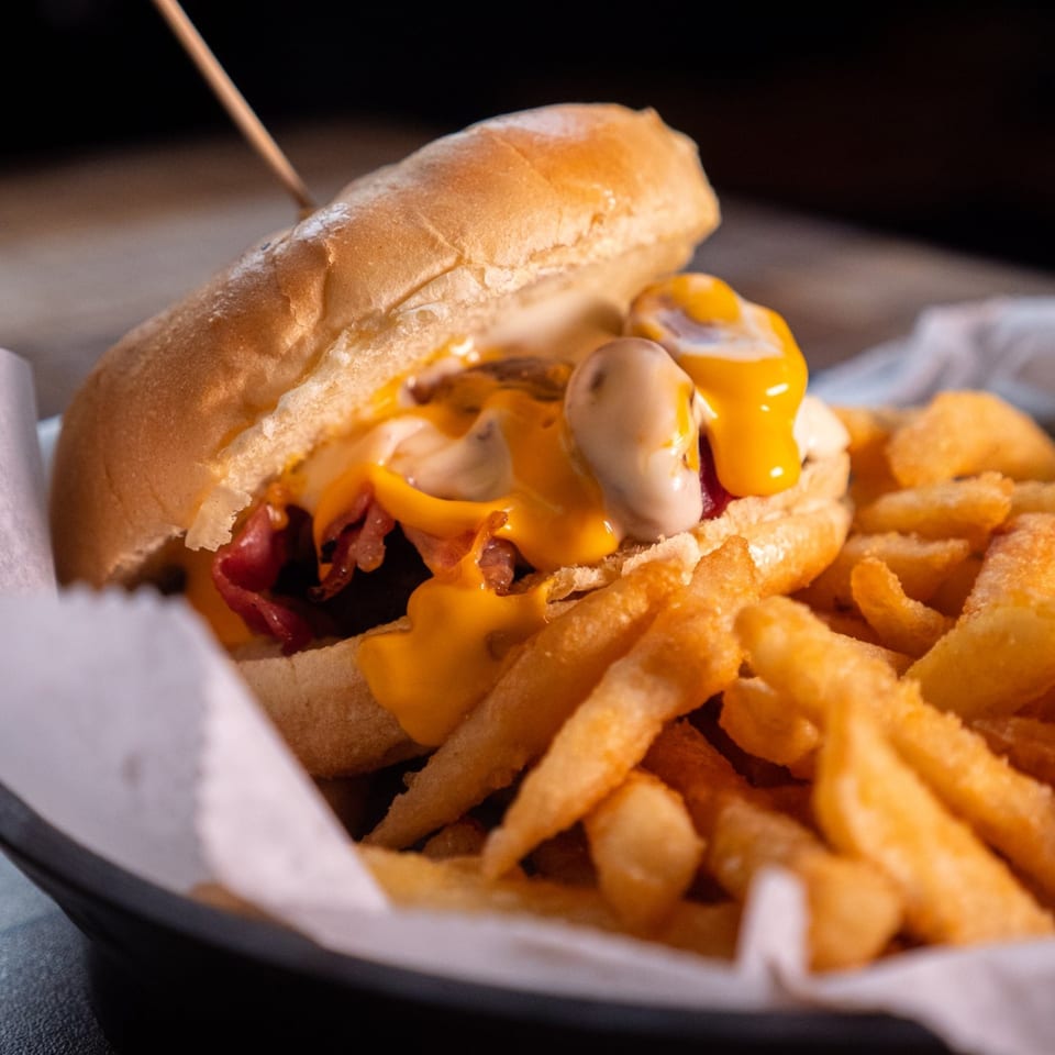 Cheesy hot dog with bacon and mushrooms, served with a side of golden french fries.