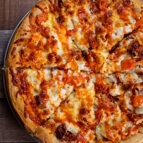 A close-up, overhead view of a freshly baked, sliced pizza with melted cheese and red sauce.