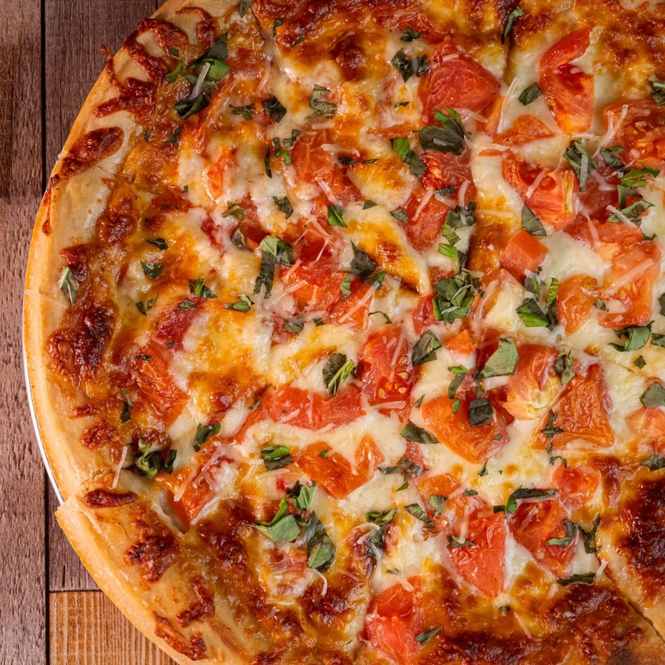 Close-up of a This Guy's Pizza Margherita pizza with fresh tomatoes, mozzarella, and basil.