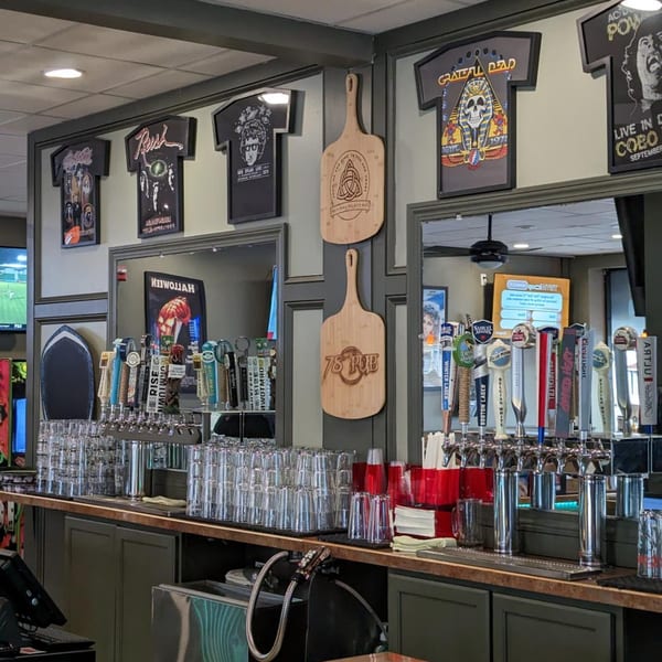 The 78 Pub bar with beer taps, stacked glasses, and framed band t-shirts on the wall.